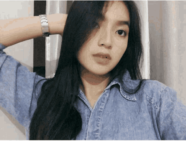 a woman wearing a blue shirt and a silver watch