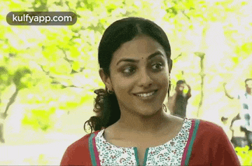 a woman is smiling and looking at the camera while standing in front of trees .