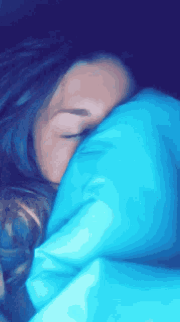 a woman is sleeping in a blue blanket