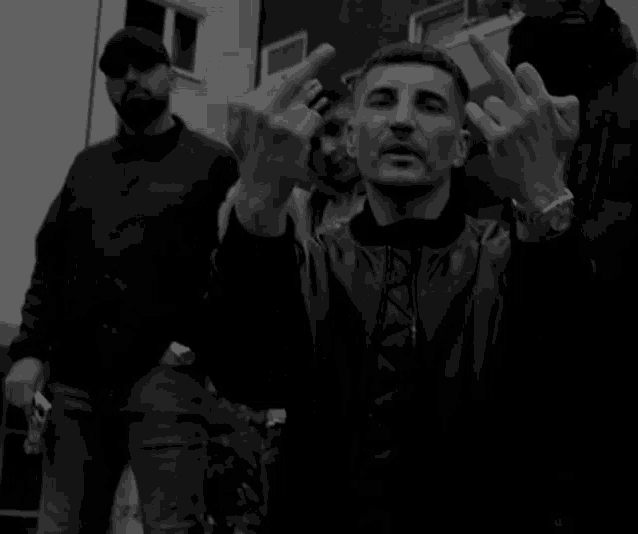 a black and white photo of three men giving the middle finger .