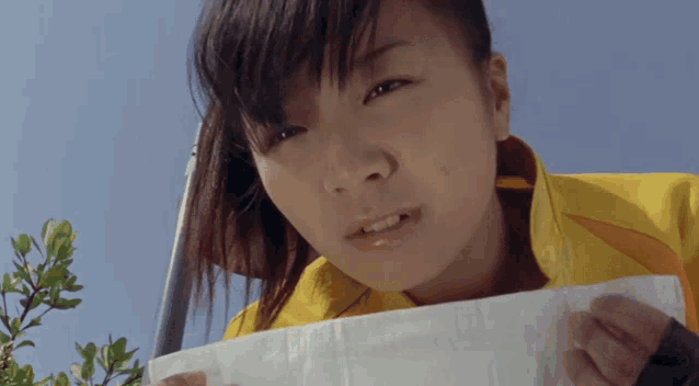 a girl in a yellow jacket holds a piece of paper