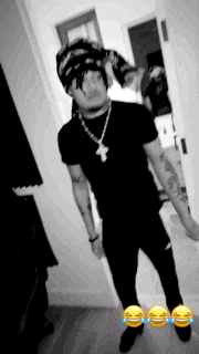 a black and white photo of a man wearing a hat and a necklace