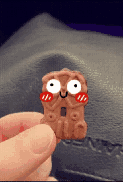 a person is holding a biscuit with a face drawn on it