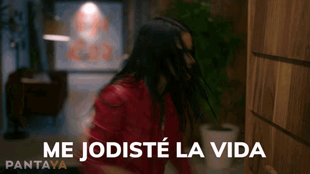 a woman in a red jacket is standing in front of a door with the words me jodiste la vida written below her