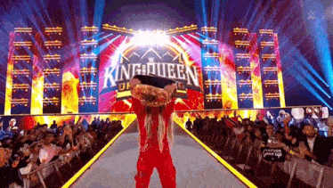 a woman in a red outfit is carrying a man in front of a sign that says king queen