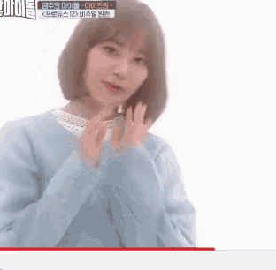 a woman with short hair is wearing a blue sweater and making a funny face .