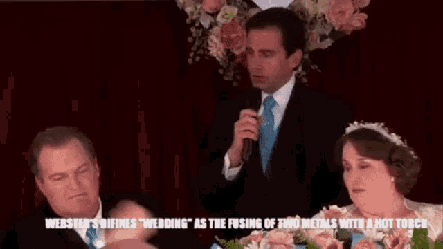 a man is holding a microphone in front of a bride and groom at a wedding reception