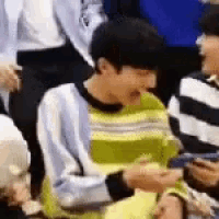 a man in a striped sweater is sitting in a crowd .