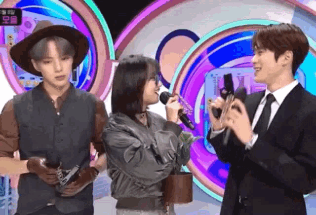 a woman singing into a microphone while a man in a suit holds a camera