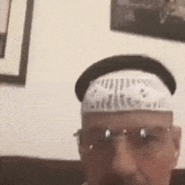 a man wearing a bandana on his head and glasses is sitting on a couch .