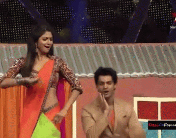 a man and a woman are dancing in front of a sign that says desi city