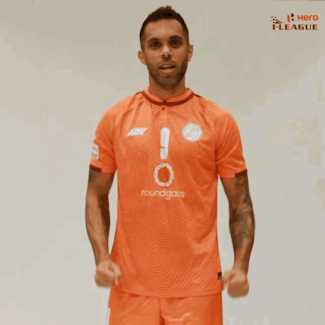 a man wearing an orange shirt that says roundgass on it