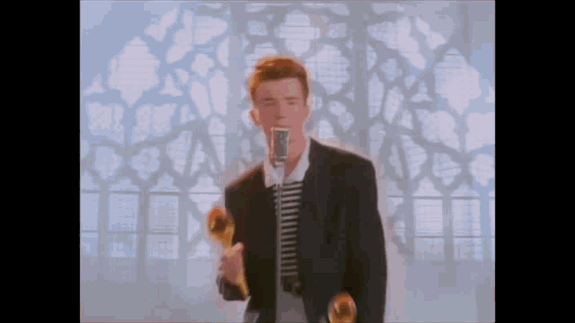 a man in a suit is singing into a microphone while holding a pair of maracas .