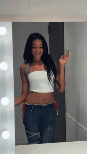 a woman standing in front of a mirror holding a cigarette