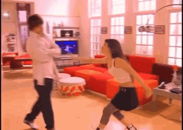 a man and a woman are dancing in a living room in front of a red couch .
