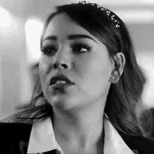 a black and white photo of a woman wearing a white shirt and a black jacket .