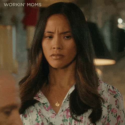 a woman in a floral shirt is making a funny face and the words workin ' moms are above her