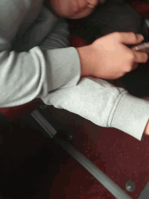 a person wearing a grey sweatshirt is using a phone
