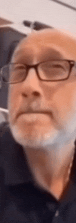 a man with glasses and a beard is wearing a face mask .