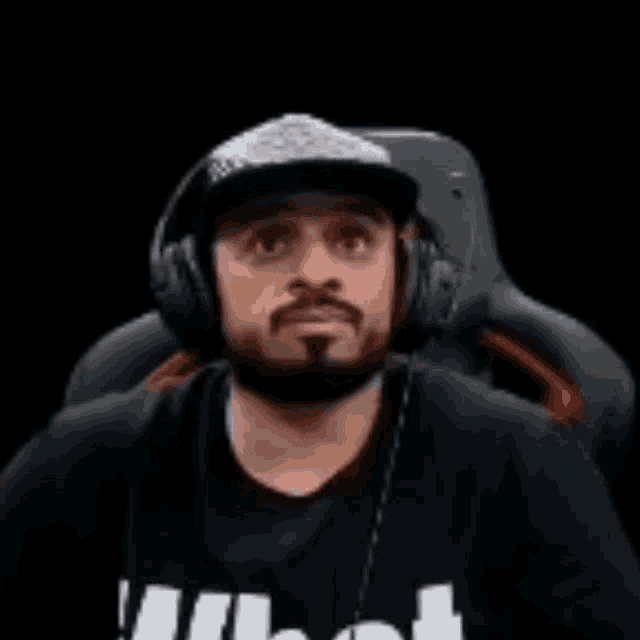 a man with a beard is wearing headphones and a baseball cap .