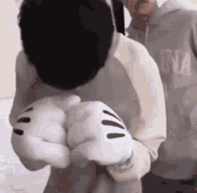 a man wearing a hoodie and mickey mouse gloves is standing next to a woman .