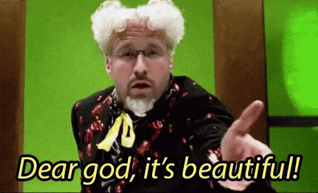 a man with white hair and a beard is pointing at the camera with the words `` dear god , it 's beautiful '' .