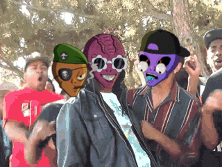 a man wearing a purple mask and sunglasses stands in a crowd of people
