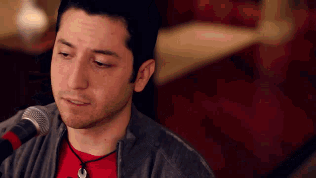 a man singing into a microphone with a red shirt