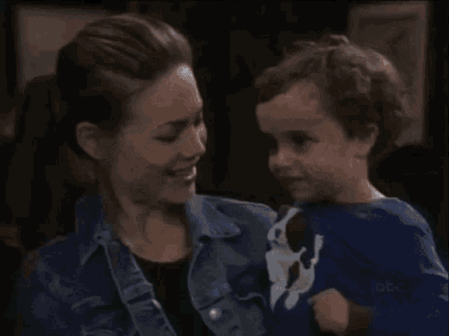 a woman is holding a small child in her arms and smiling .
