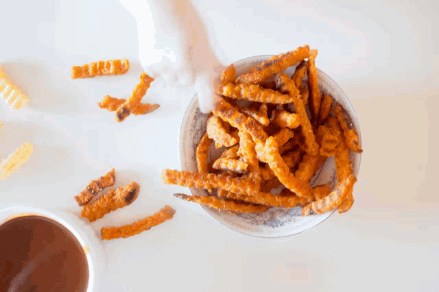 a bowl of french fries and a cup of dipping sauce