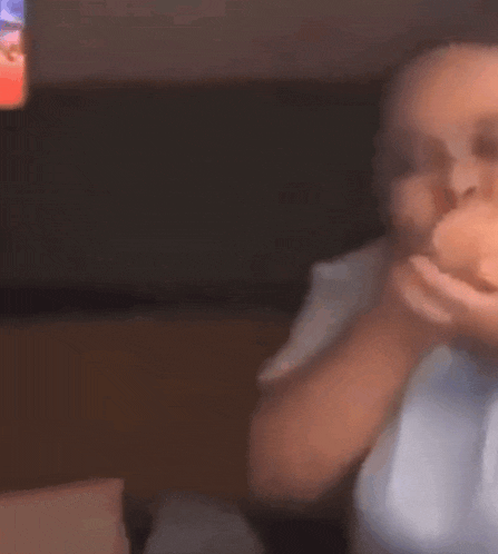 a blurry picture of a person eating a donut in front of a tv .