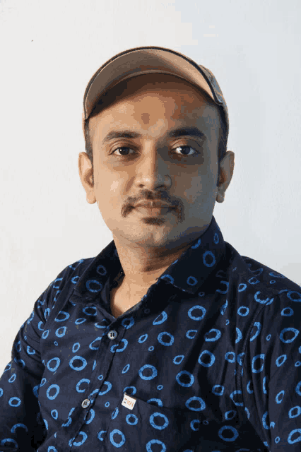 a man wearing a blue shirt with circles on it and a hat