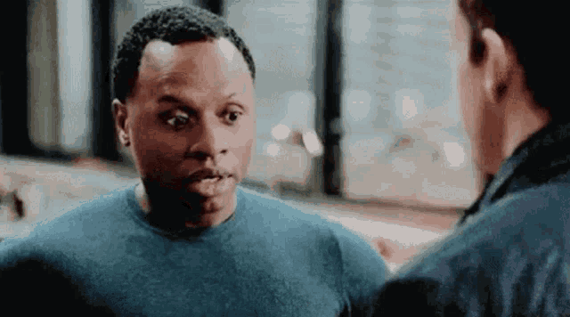 a man in a blue shirt is talking to another man in a blue jacket .