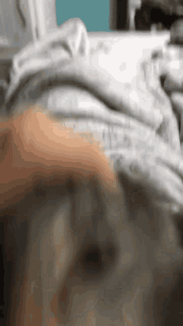 a blurry picture of a person laying on a bed with white sheets