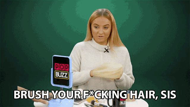 a woman brushes her hair in front of pop buzz