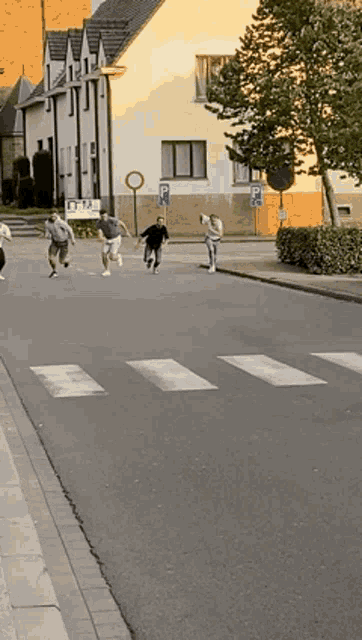 a group of people are running down a street in front of a building with a sign that says p on it