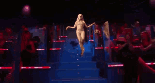 a naked woman is walking down a stage in front of a crowd .