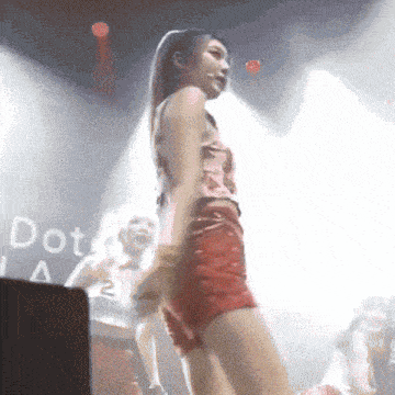 a woman in red shorts is dancing on a stage in front of a sign that says dot la
