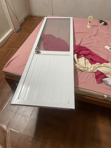 a bed with a pink blanket and a white door that says ' lotte ' on it