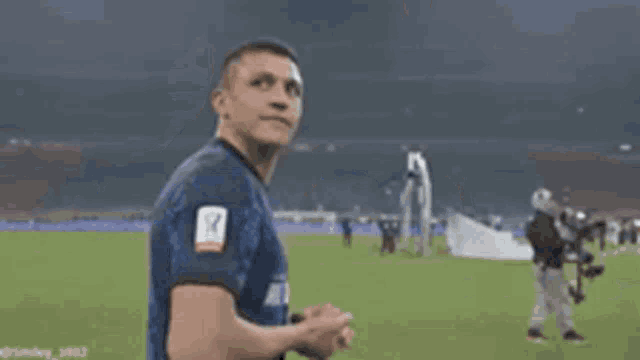 a man covering his mouth with his hands while standing on a soccer field .