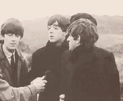 a group of young men are standing next to each other and talking to each other in a black and white photo .