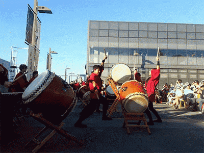 a group of people are playing drums outside in front of a building