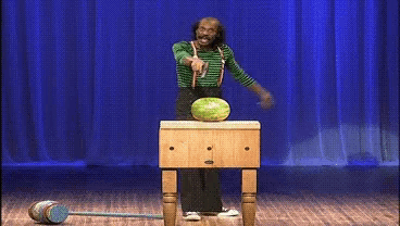 a man is standing at a podium with a watermelon in front of him