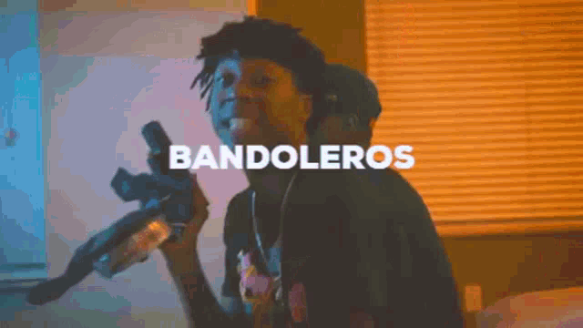 a video of a man holding a gun with the words bandoleros written above him .