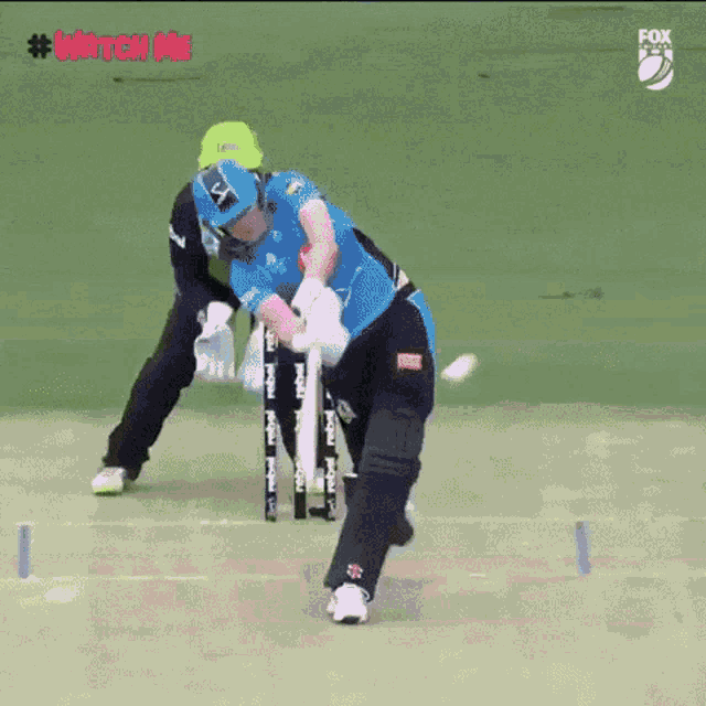 a cricket player is getting ready to hit the ball while another player watches