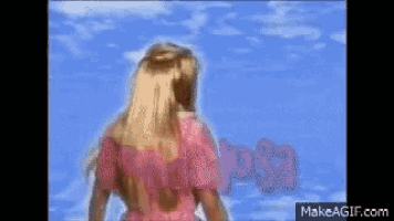 a barbie doll in a pink dress stands in front of a blue sky .