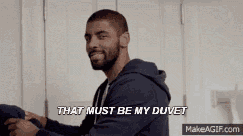 a man is standing in a laundry room folding clothes and says `` that must be my duvet '' .