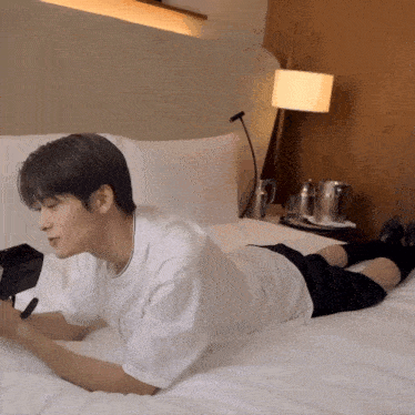 a young man is laying on a bed with his legs crossed
