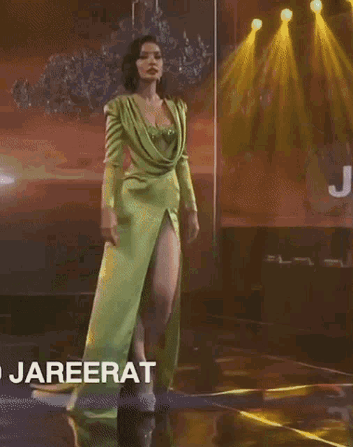 a woman in a green dress is walking down a runway in front of a sign that says jaf
