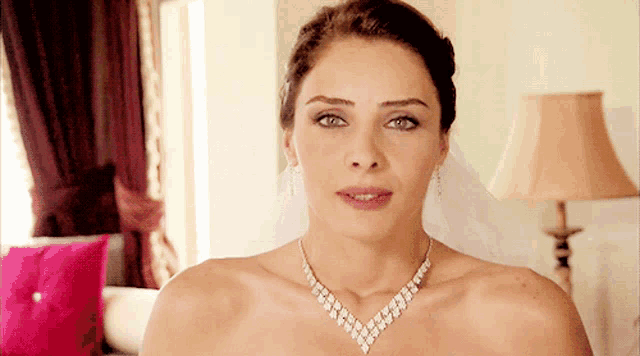a woman wearing a diamond necklace and earrings is looking at the camera